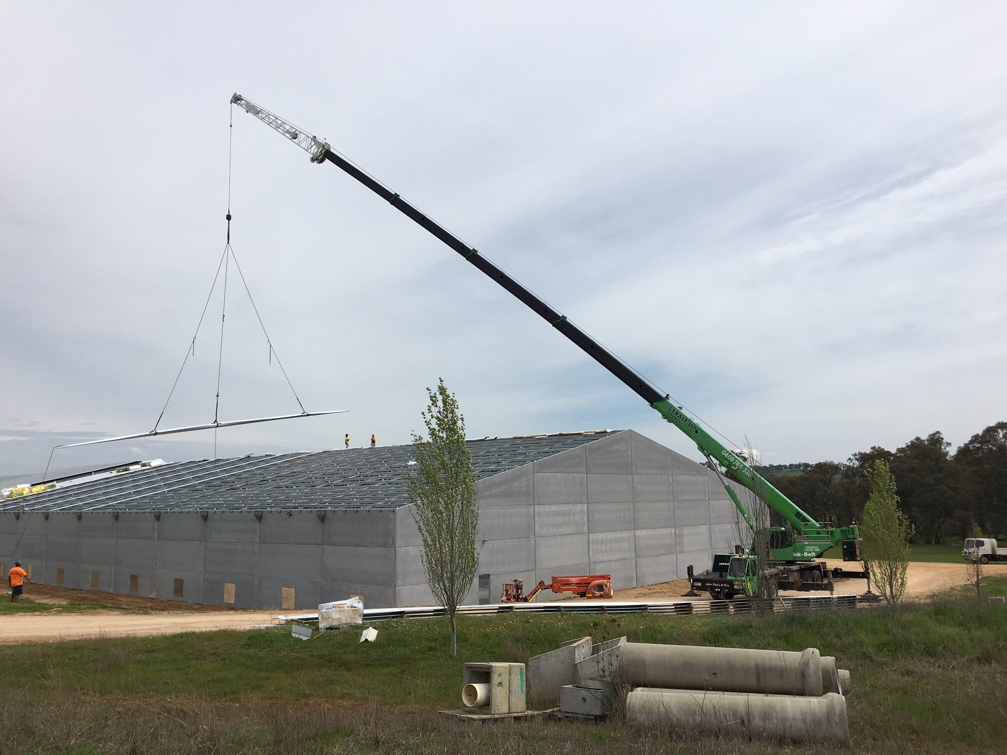 Crane placing roof sheets onto a shed
